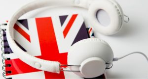 formation anglais sur se perfectionner ses compétences orales en anglais- casque et carnet avec drapeau anglais