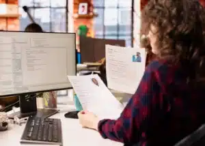 Recruteur comparant des CV papier avec des données analysées par intelligence artificielle sur écran pour optimiser les processus RH.