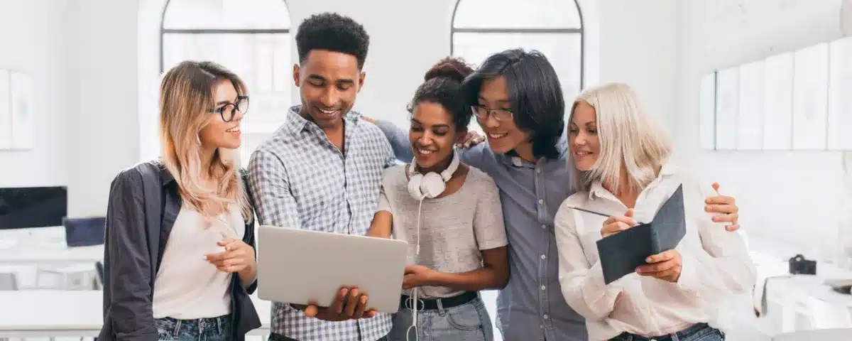 Groupe diversifié de jeunes collaborateurs heureux de travailler ensemble sur un projet. L'inclusion des jeunes est un levier clé pour la performance et l'innovation.