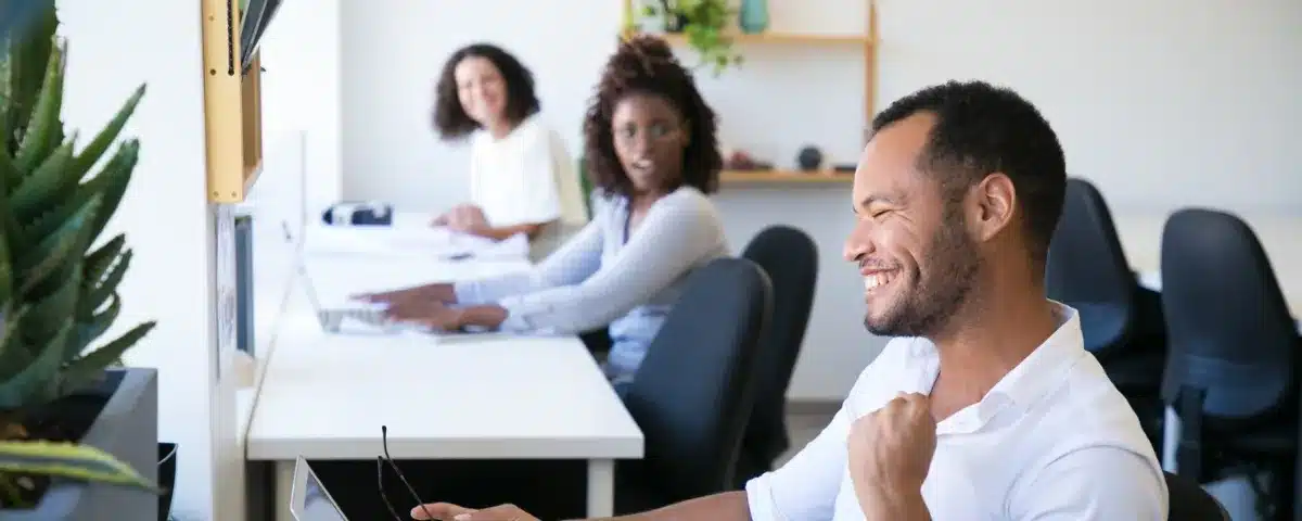 Collaborateur célébrant une réussite au bureau, symbolisant une meilleure gestion du temps et un bien-être retrouvé après la régulation des outils numériques.