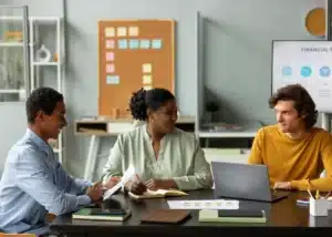 Trois collaborateurs concentrés lors d'une réunion de travail dans un bureau moderne.