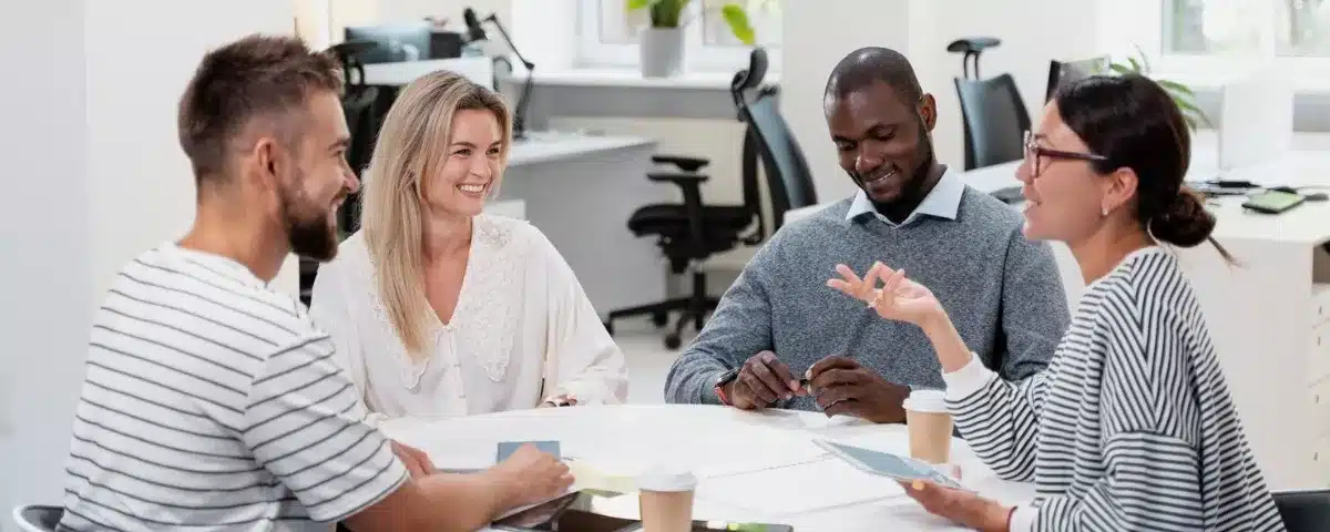Quatre collaborateurs réunis autour d'une table échangeant un feedback constructif au bureau.